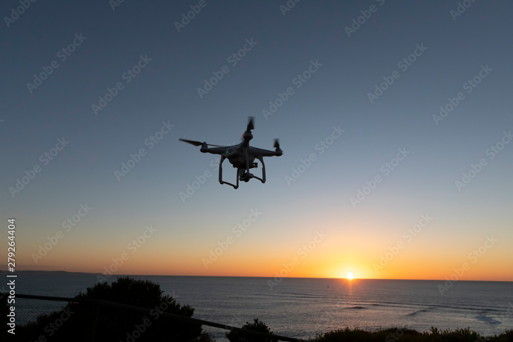 Professional or Prosumer Drone flying over the sea at Sunrise Professional or Prosumer Drone flying over the sea at Sunrise