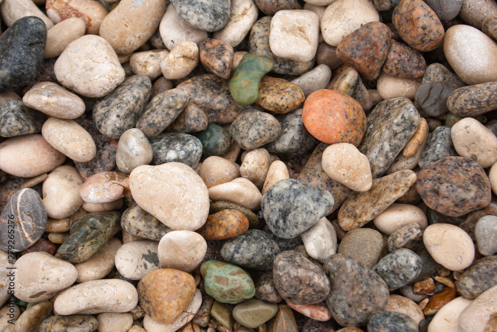Seashore with gravel stone in summer, close up view. Texture of jackstone. Multicolour pebbles, abstract background