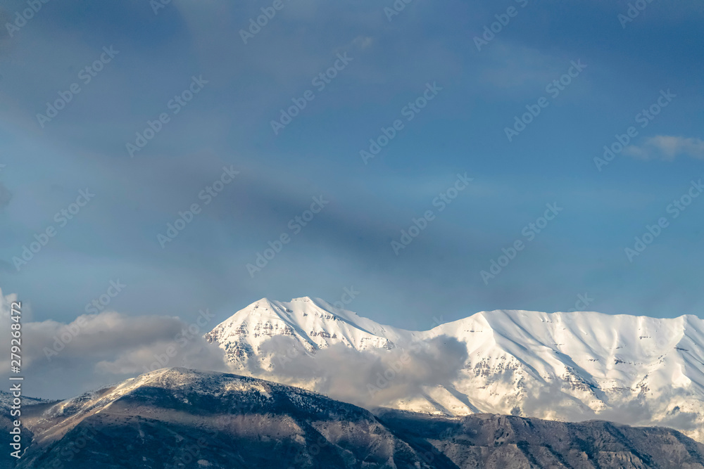 Beautiful view of a mountain with its peak covered with sunlit white snow