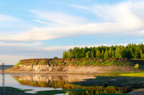 The steep slope of the shore with different soil clay and sand from the Northern rivers of Yakutia, the Vilyuy bright day in the tundra. photo