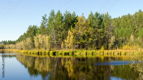 Ripples from the wind runs through the clean surface of the water with the reflection of the Northern forest and trees in the wild secluded taiga of Northern Yakutia. photo