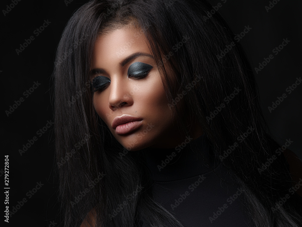 Fototapeta premium Zbliżenie modny portret pięknej młodej kobiety mulat z zamkniętymi oczami, pełnymi ustami i czarnymi bujnymi luźnymi włosami. Studio strzelać African American modelki z jasnym makijażem na twarzy
