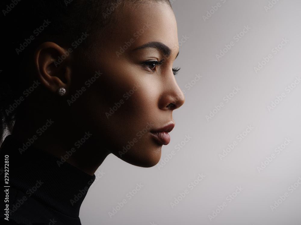 Closeup fashionable portrait of a metis young woman with perfect smooth  glowing mulatto skin, full lips, collected hair and long neck. Studio photo  of an african american female model face, profile Stock