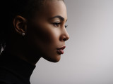 Closeup fashionable portrait of a metis young woman with perfect smooth glowing mulatto skin, full lips, collected hair and long neck. Studio photo of an african american female model face, profile
