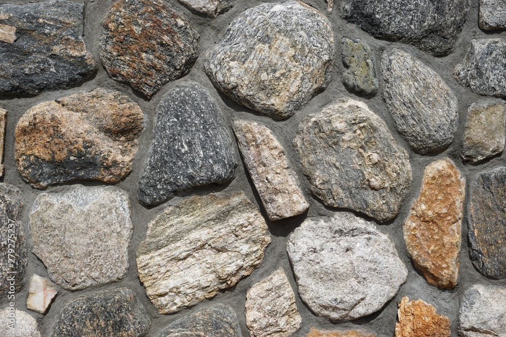 Rough stone wall with irregular rocks set in gray mortar Rough stone wall with irregular rocks set in gray mortar