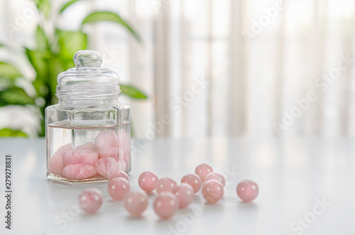 Bilde på lerret Tumbled rose quartz stones are placed inside of a glass jar with drinking water