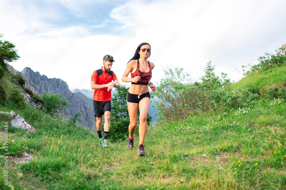 Athletic trainer measures the time of an athlete female race woman in the mountain