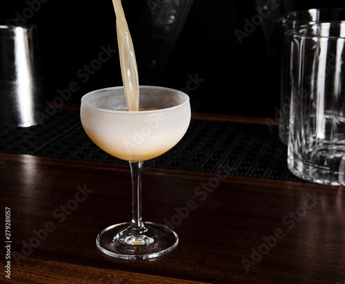 Orange cocktail being poured into a chilled glass