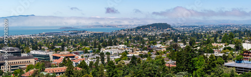 View towards Berkeley, Richmond and the San Francisco bay area shoreline on a sunny day; University of California Berkeley campus buildings in the foreground, California