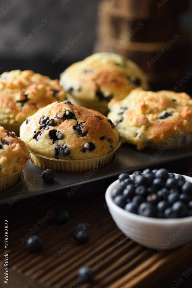 Freshly baked muffins and wild bilberries on oak cutting board copy space. Low key still life with natural lighting Freshly baked muffins and wild bilberries on oak cutting board copy space. Low key still life with natural lighting