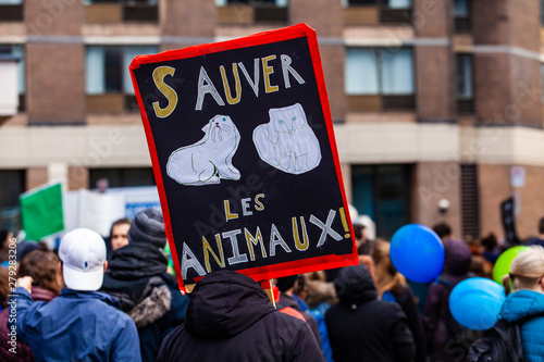 Ecological activists march for change. A French sign is seen closeup in a crowd of protestors saying save the animals as environmental demonstrators march on an urban city street. © Valmedia