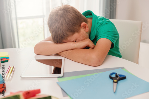 Schoolboy crying or sleeping at his desk at home