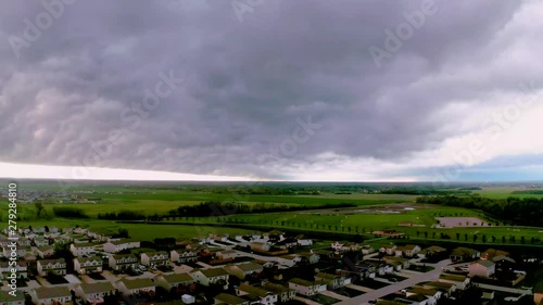 Dramatic storm cloud cover over Steinbach residential town property & fields, Canada. Aerial dolly right. photo