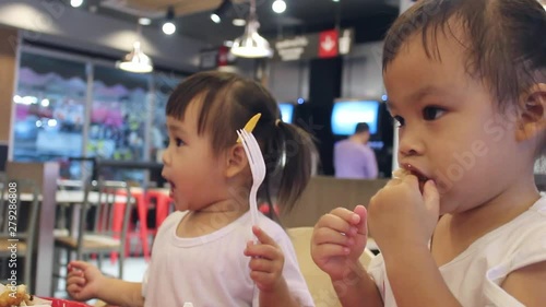 Happy Asian children are eating delicious French fries and drink some necta with her mother in restaurants. photo