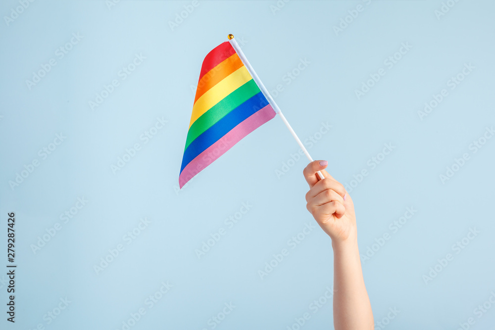Gay flags in women's hand on grey background Gay flags in women's hand on grey background
