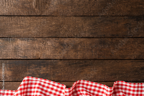 Red checkered tablecloth on wooden background with copyspace
