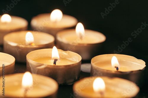 Burning candle on table in darkness  space for text. Funeral symbol