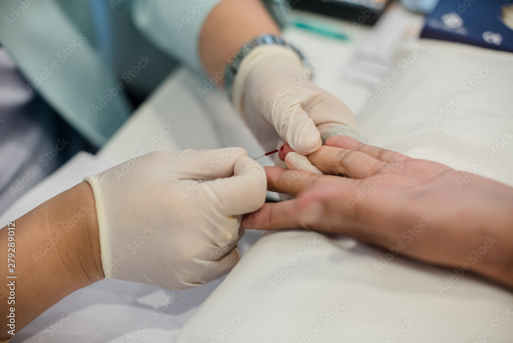 Blood collection staff are using a needle to penetrate the fingertip to check blood sugar levels. Blood collection staff are using a needle to penetrate the fingertip to check blood sugar levels.