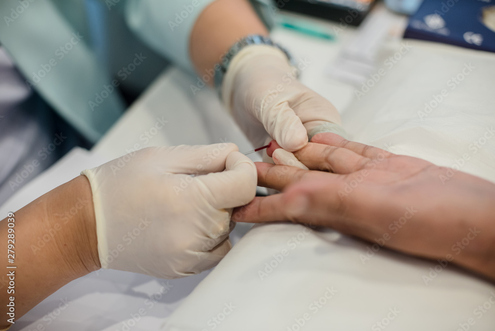 Blood collection staff are using a needle to penetrate the fingertip to check blood sugar levels. Blood collection staff are using a needle to penetrate the fingertip to check blood sugar levels.