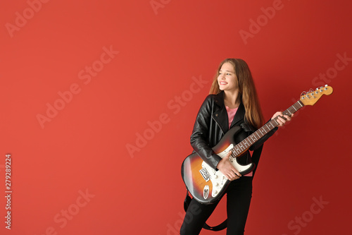 Teenage girl playing guitar against color background