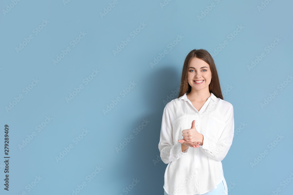 Young deaf mute woman using sign language on color background Young deaf mute woman using sign language on color background
