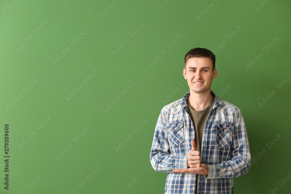 Young deaf mute man using sign language on color background Young deaf mute man using sign language on color background