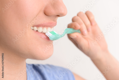 Woman with toothbrush on light background, closeup. Concept of dental hygiene