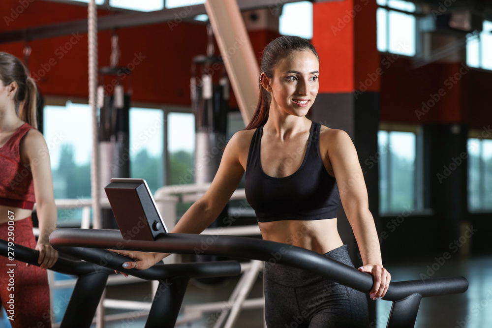 Fototapeta premium Sporty young woman on treadmill in gym