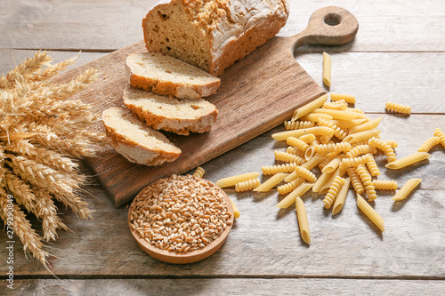 Fresh bread with pasta and wheat grains on wooden table