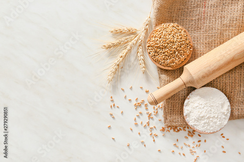 Fotografie Rolling pin with wheat grains and flour on light background