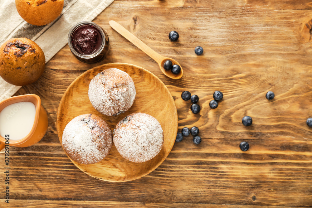 Tasty blueberry muffins with jam and milk on wooden table Tasty blueberry muffins with jam and milk on wooden table