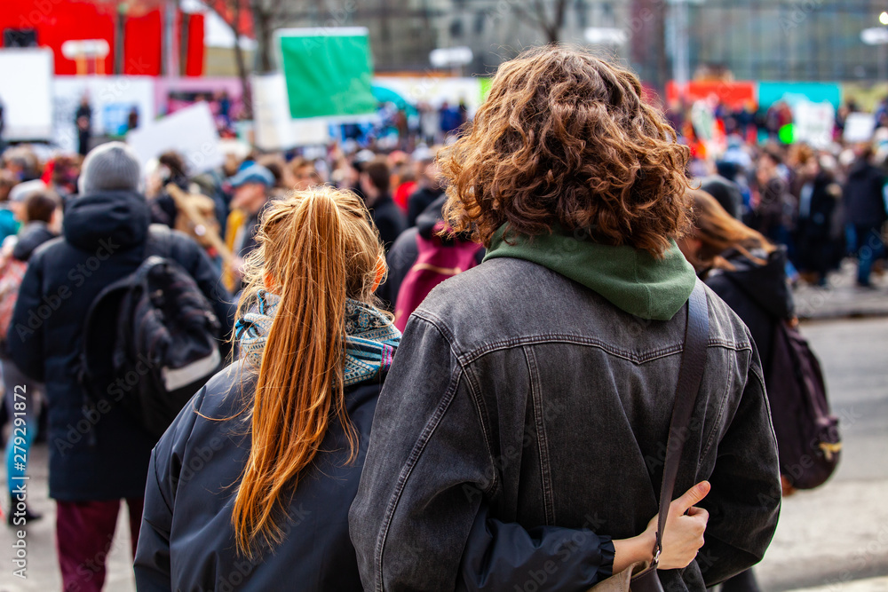 People gather for climate change. Two young people are seen from the back, watching a crowded demonstration of people against global warming on a street in Montreal, Canada