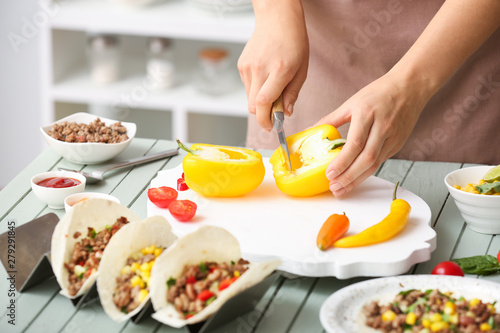 Woman preparing tasty fresh tacos in kitchen