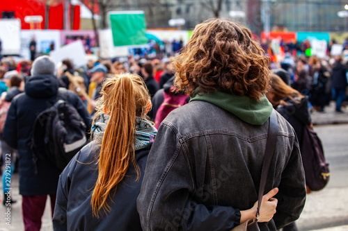 People gather for climate change. Two young people are seen from the back  watching a crowded demonstration of people against global warming on a street in Montreal  Canada