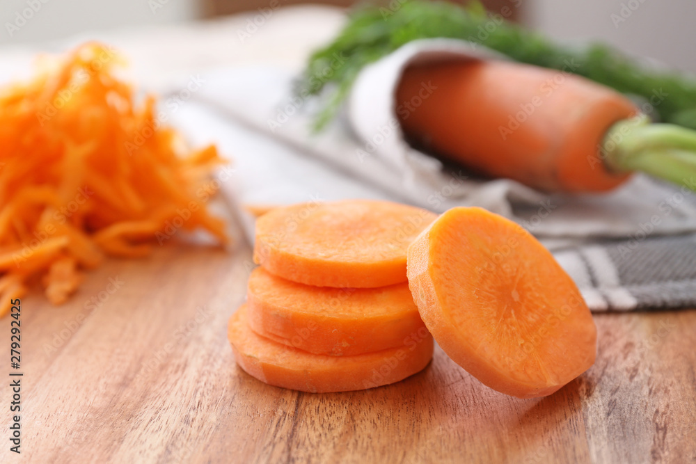 Slices of fresh carrots on wooden board, closeup