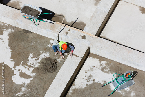 Uniformed workers clean sand on a construction site, top view.