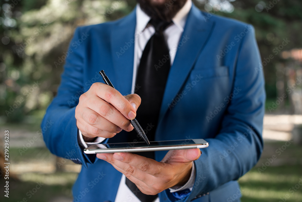 Businessman in blue suite stands with mobile phone in hands. Businessman in blue suite stands with mobile phone in hands.