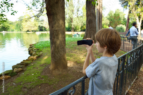 Little boy with video camera shoots a story about nature at Villa Borghese in Rome, Italy. young video blogger busy favorite hobby photo