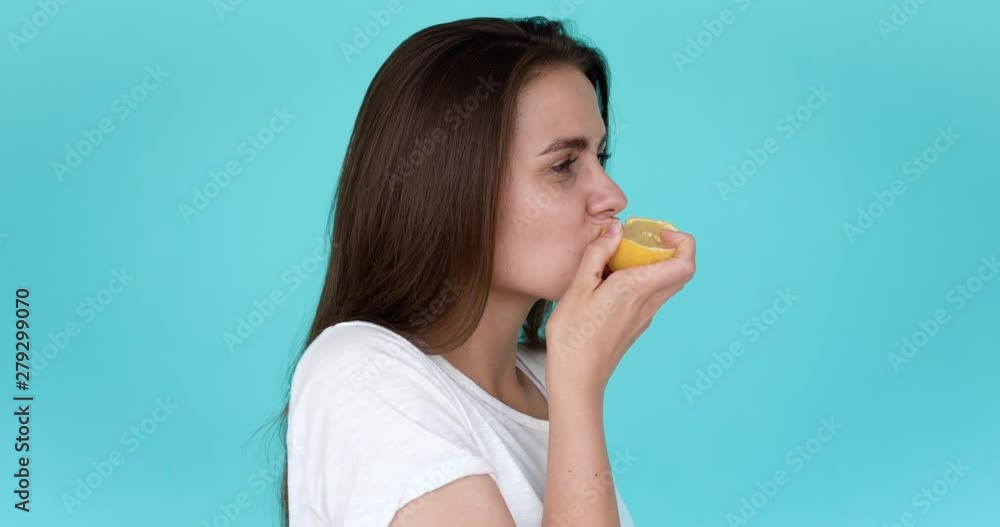 Brunette girl bites lemon. Portrait in profile. Yellow sour lemon. Brunette girl bites lemon. Portrait in profile. Yellow sour lemon.