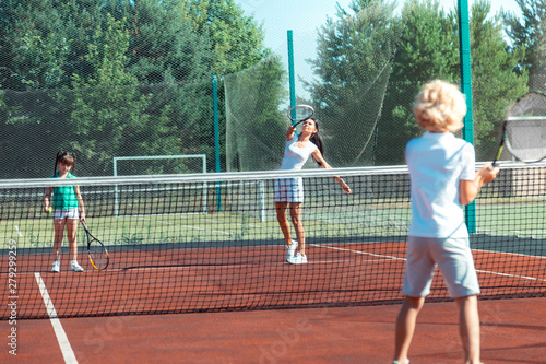 Dark-haired mother playing tennis with children at the weekend © Viacheslav Yakobchuk