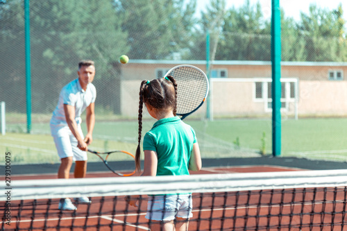 Daughter feeling involved in playing tennis with father © Viacheslav Yakobchuk