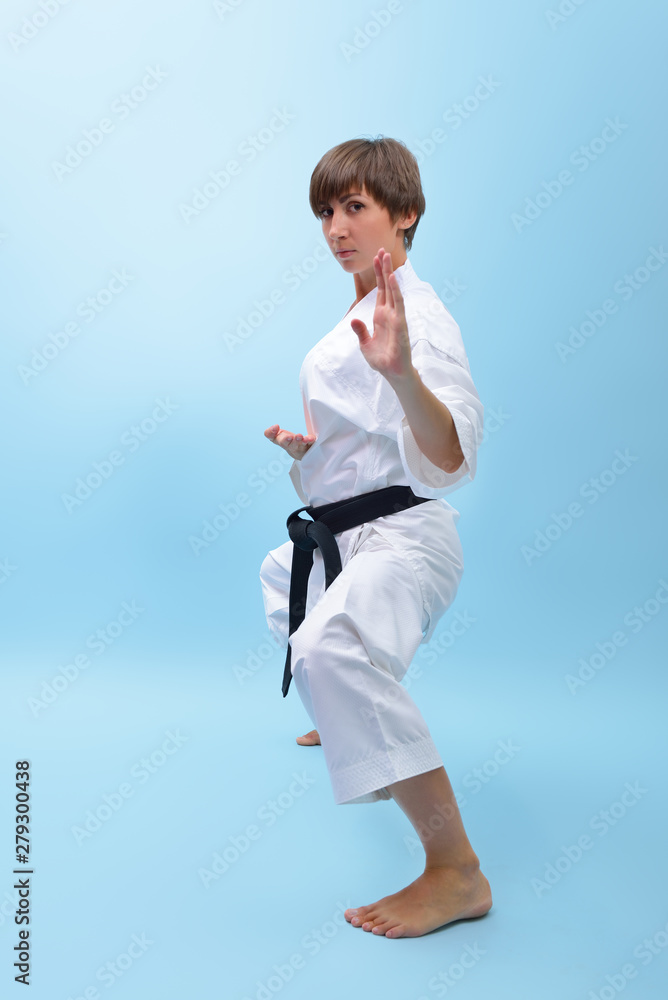 Young karate woman in a white kimono with black belt demonstrates