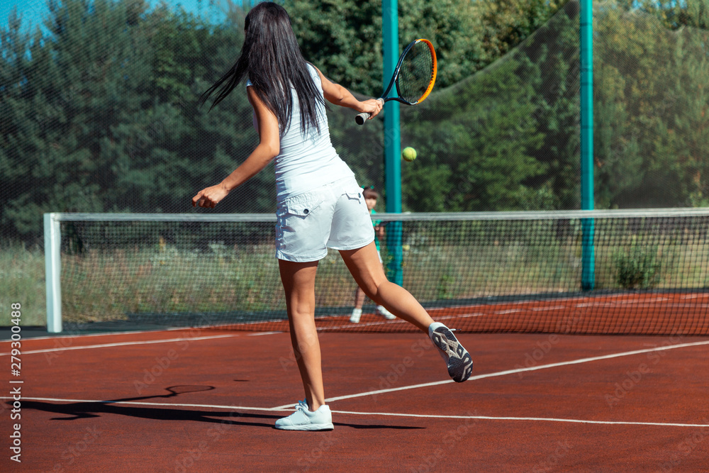 Fit mommy wearing white shorts playing tennis with daughter