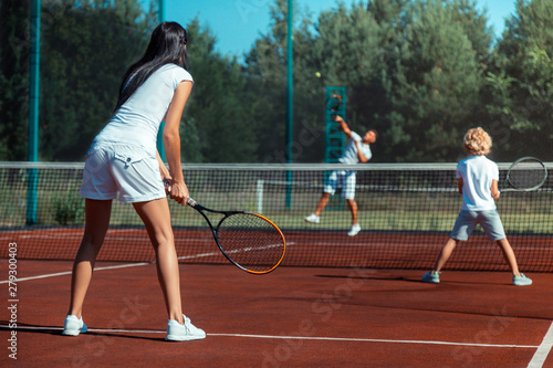 Dark-haired wife playing tennis with husband and son