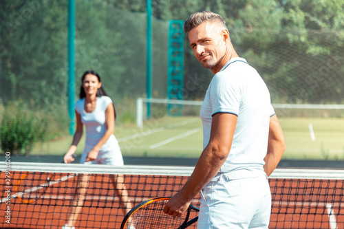 Handsome athletic man playing tennis with wife
