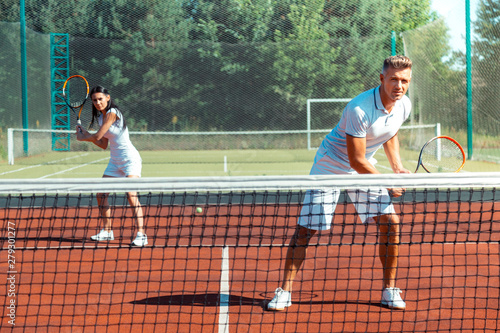 Couple feeling joyful while training on court playing tennis © Viacheslav Yakobchuk