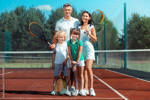 Parents and children feeling happy and cheerful after playing tennis