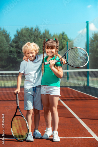Brother and sister hugging while feeling happy after playing tennis © Viacheslav Yakobchuk