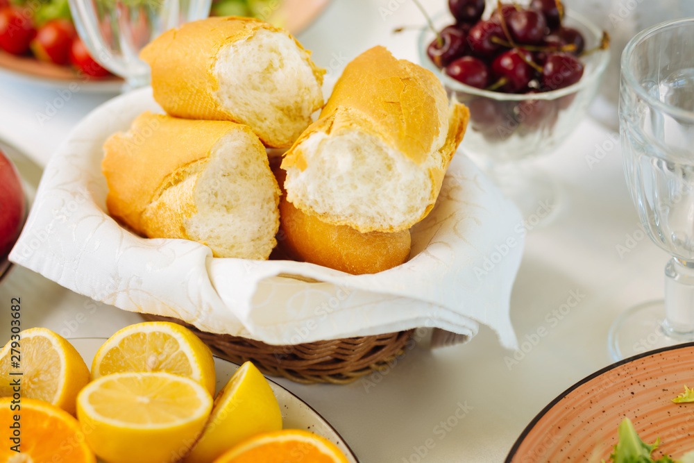 Pieces of baguette lying in bowl near lemons and cherries Pieces of baguette lying in bowl near lemons and cherries
