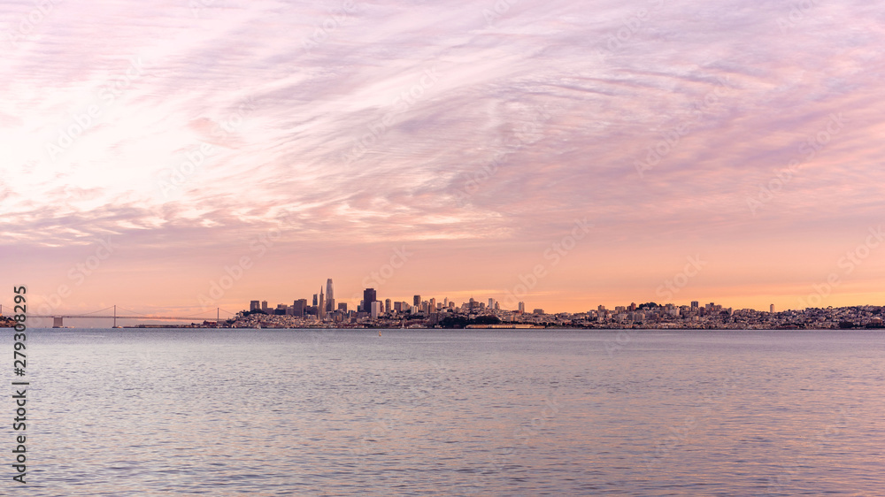 San Francisco downtown panorama at sunset with edge of ocean and fancy clouds.